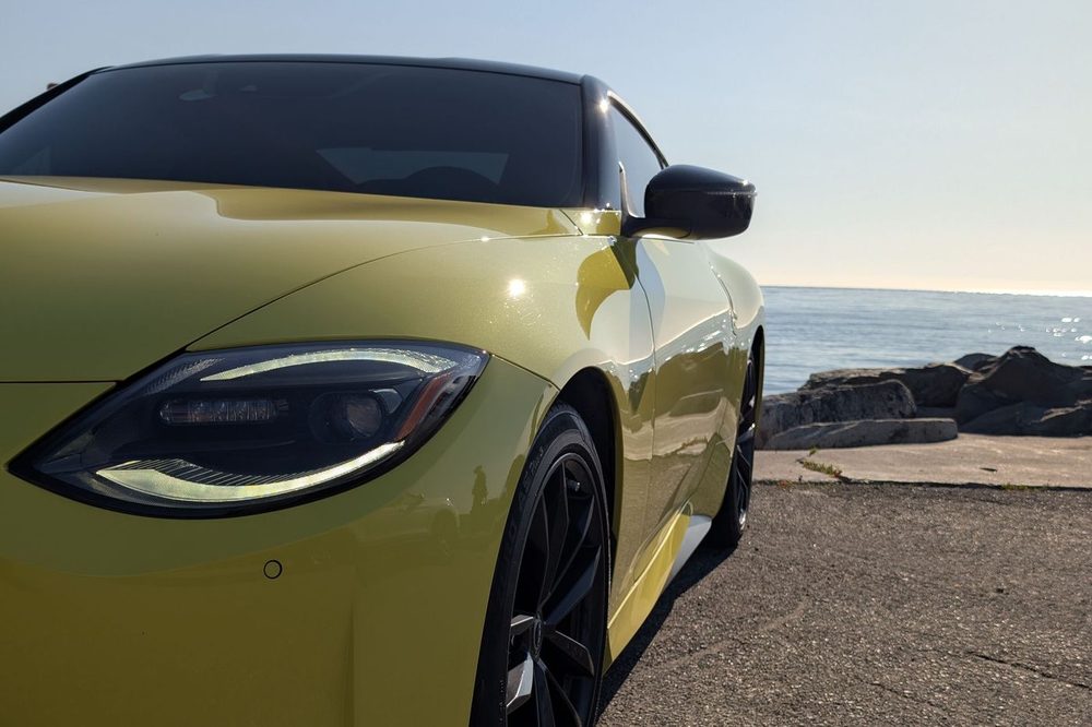Yellow Nissan Z with a fresh ceramic coating, parked by the water